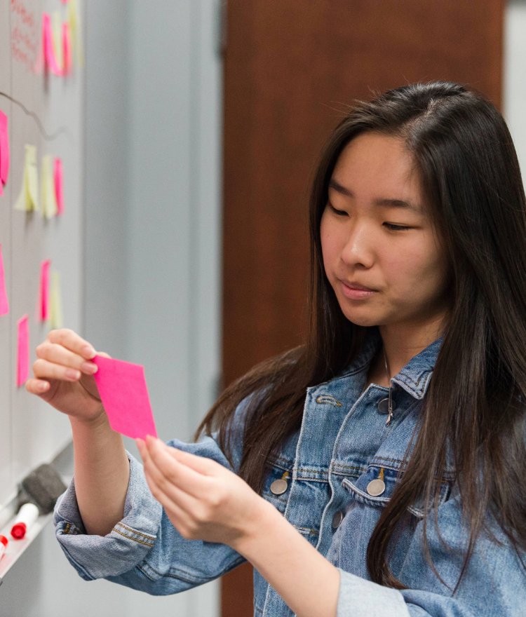 Female engineering student reading notes off of a post it note.