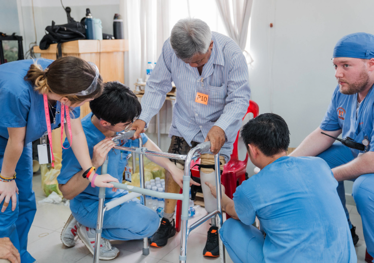students assisting a patient with their prosthetic leg fitting