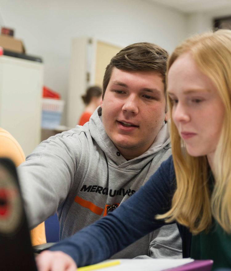 male engineering student pointing to a laptop and talking to a female engineering student