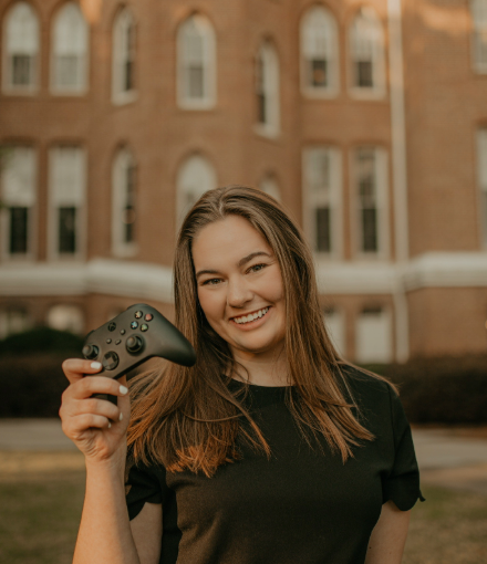 woman smiling at camera while holding game controller